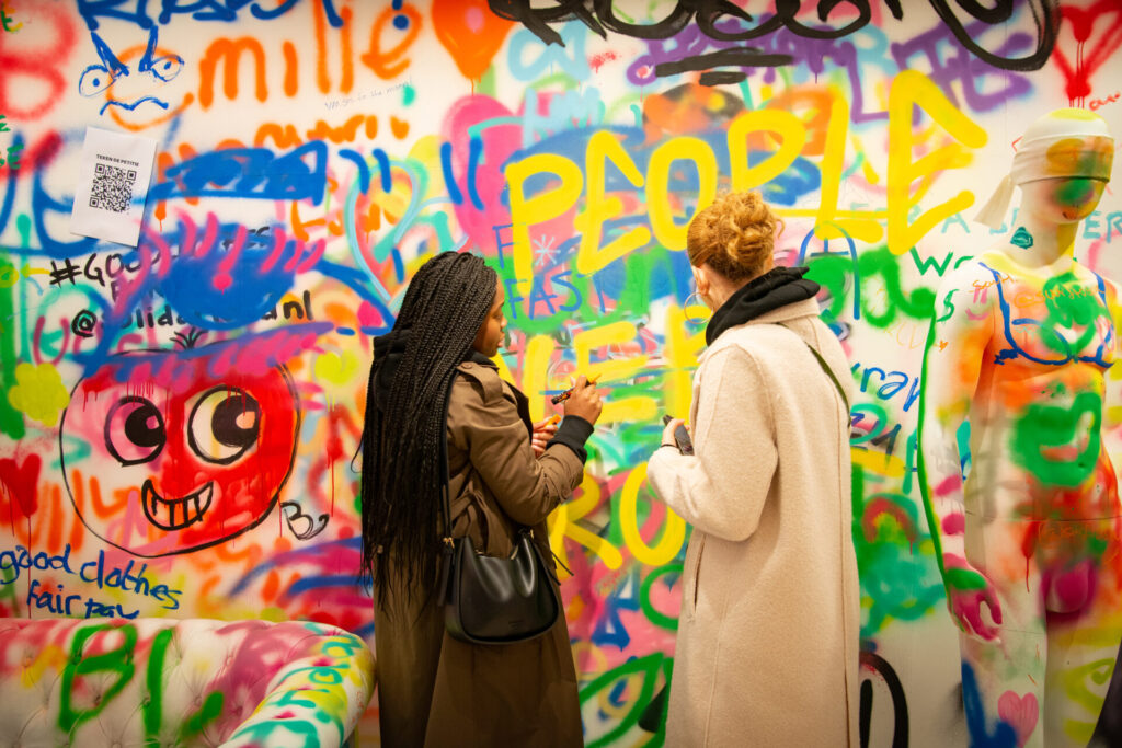 Zwei Frauen stehen vor bunter Graffiti-Wand