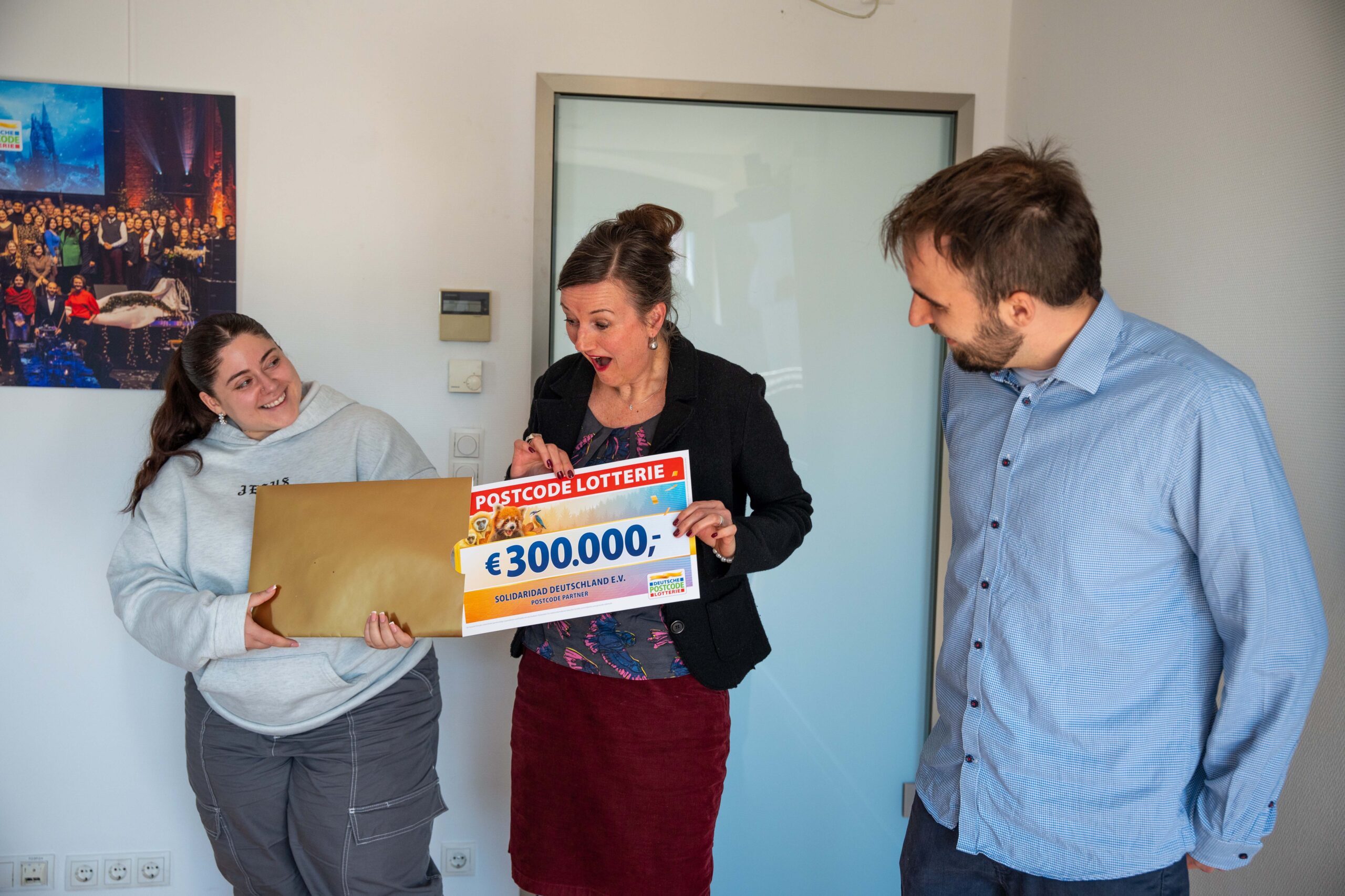 Vertreterin von Solidaridad Deutschland reagiert überrascht und erfreut beim Erhalt des symbolischen 300.000-Euro-Schecks der Postcode Lotterie.