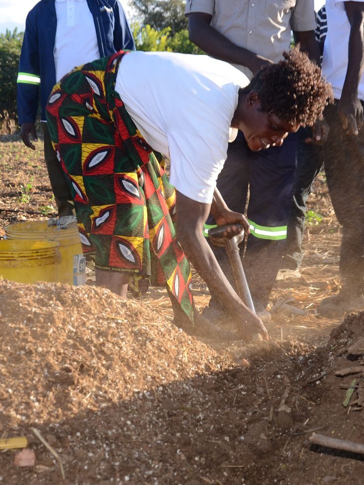 Eine sambische Frau bearbeitet mit einem Spaten die ausgetrocknete Erde – Teil des Solidaridad-Projekts zur nachhaltigen Landwirtschaft trotz extremer Trockenheit.