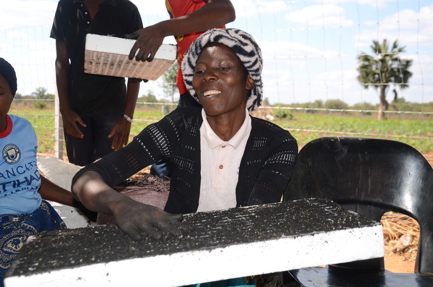 Prisca Nsondo aus Sambia hält eine Pflanzschale in der Hand und setzt sorgfältig Samen ein – Teil des Solidaridad-Projekts zur Förderung nachhaltiger Ernährung in von Dürre betroffenen Regionen.